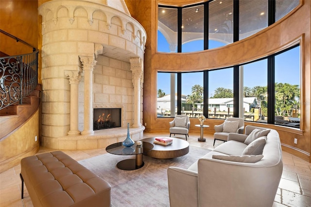 living area with a healthy amount of sunlight, stone tile floors, a high ceiling, and a stone fireplace