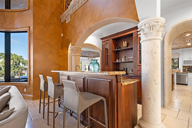 bar with arched walkways, decorative columns, stone tile floors, a towering ceiling, and dishwasher