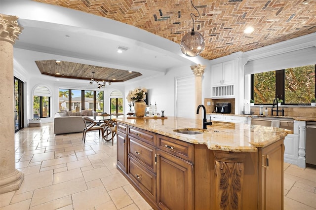 kitchen featuring stone tile flooring, brick ceiling, a spacious island, and a sink