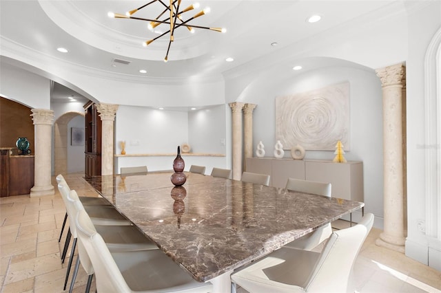 dining area with arched walkways, a raised ceiling, stone tile floors, and ornate columns