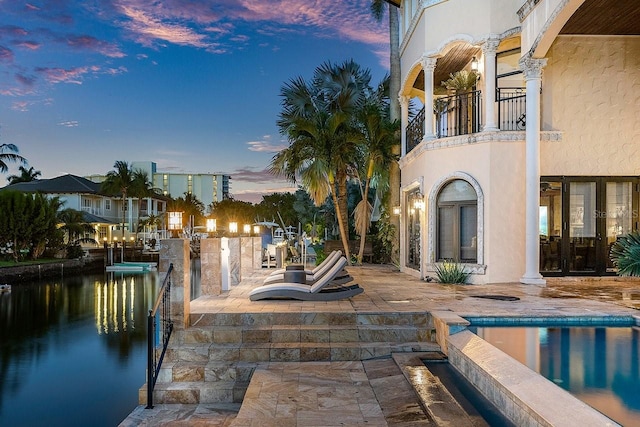 exterior space with a patio, a boat dock, a water view, and an outdoor pool