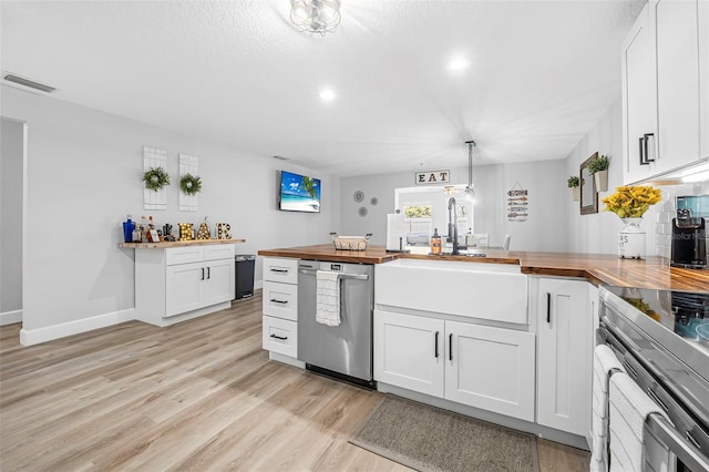 kitchen featuring white cabinets, wooden counters, decorative light fixtures, and appliances with stainless steel finishes