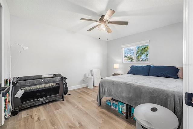 bedroom with ceiling fan, light hardwood / wood-style floors, and a textured ceiling