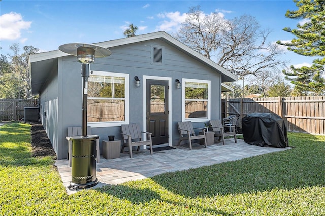 back of house featuring central AC unit, a patio area, and a lawn