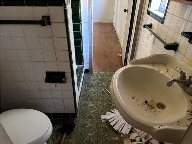 bathroom with toilet, tile walls, and sink