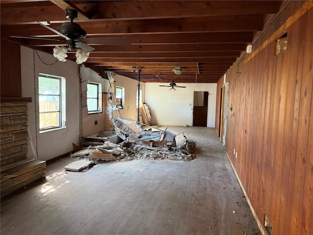 misc room featuring wood walls, ceiling fan, and beam ceiling