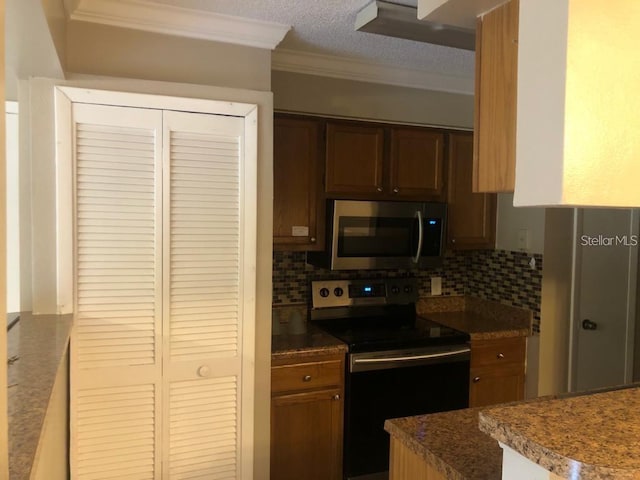 kitchen featuring a textured ceiling, crown molding, stainless steel appliances, and tasteful backsplash