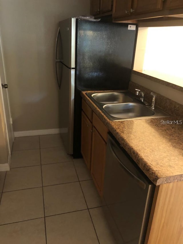 kitchen featuring stainless steel refrigerator, dishwasher, light tile patterned floors, and sink