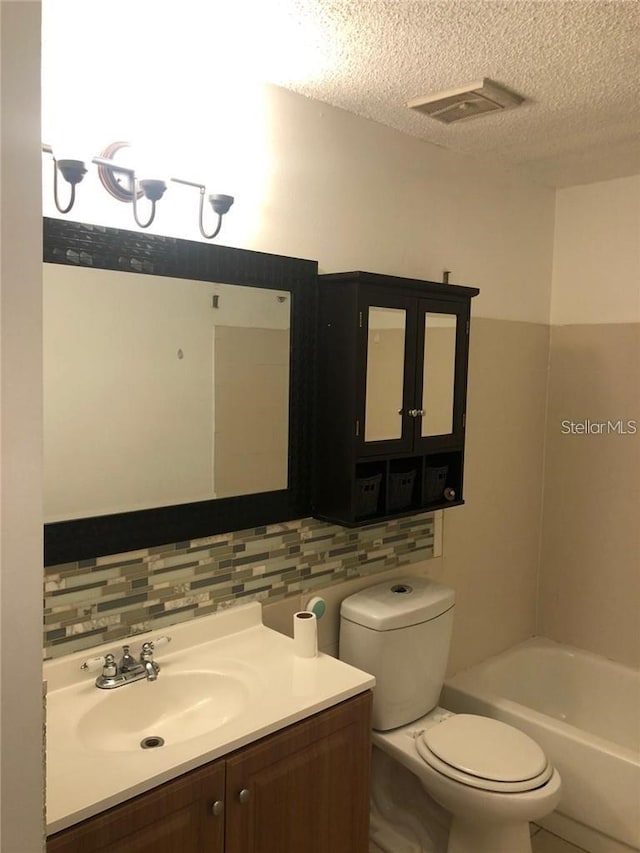 bathroom with backsplash, a bath, and a textured ceiling