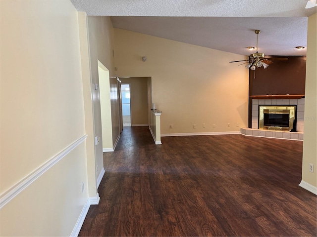 unfurnished living room with ceiling fan, vaulted ceiling, a fireplace, dark wood-type flooring, and a textured ceiling