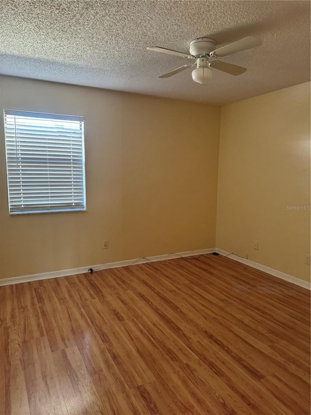 empty room with ceiling fan, a textured ceiling, and hardwood / wood-style floors