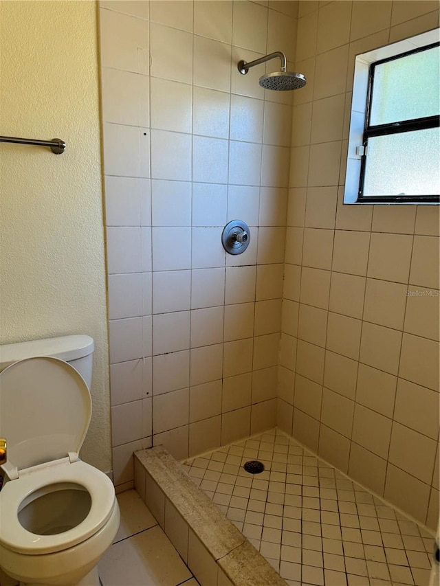 bathroom featuring toilet, tile patterned floors, and a tile shower