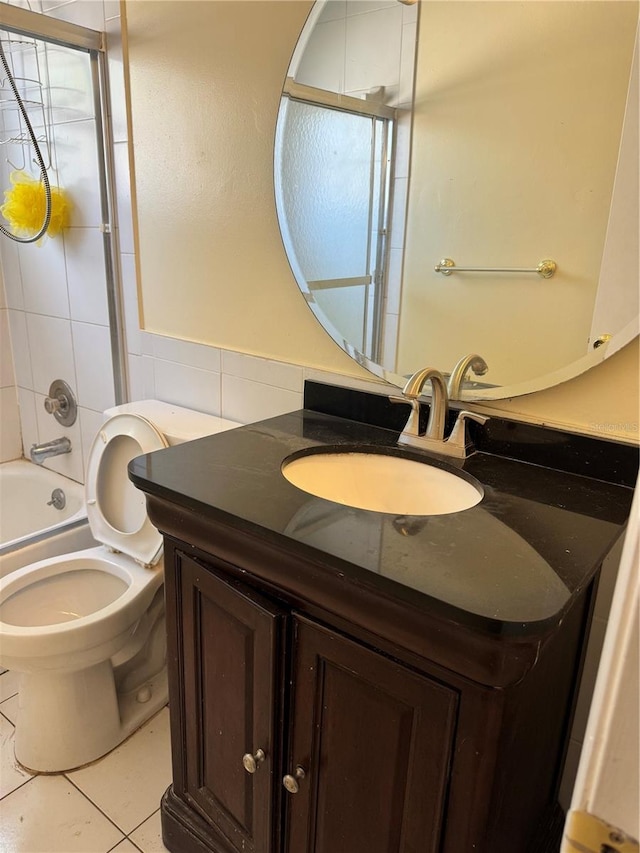 full bathroom with toilet, vanity, tile walls, tile patterned flooring, and tiled shower / bath combo