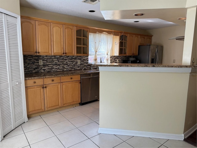 kitchen featuring backsplash, appliances with stainless steel finishes, light tile patterned flooring, and dark stone counters