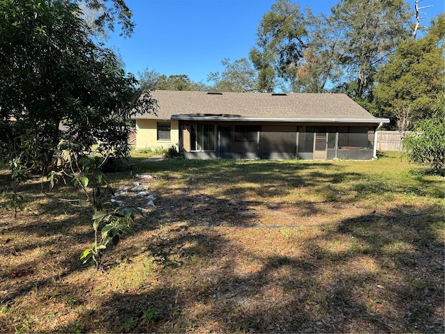 rear view of house featuring a sunroom and a yard