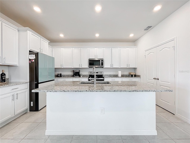 kitchen with white cabinets, sink, an island with sink, appliances with stainless steel finishes, and light stone counters