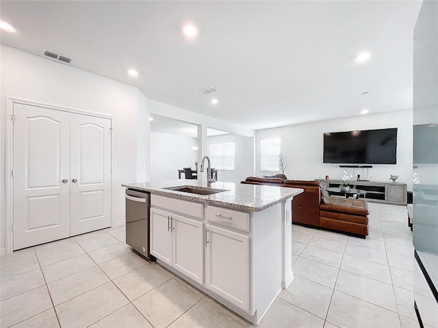 kitchen featuring light stone countertops, a kitchen island with sink, sink, white cabinetry, and light tile patterned flooring