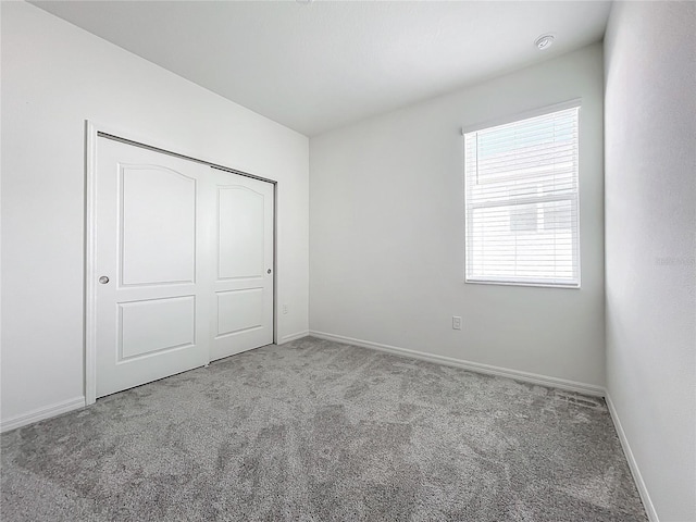 unfurnished bedroom featuring light colored carpet and a closet