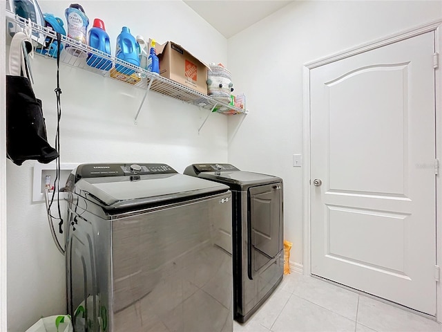 clothes washing area featuring light tile patterned floors and washing machine and dryer