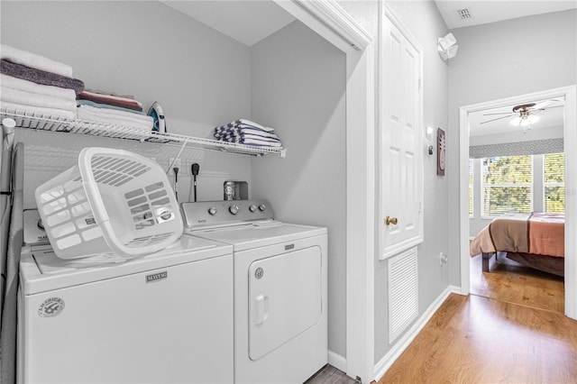 clothes washing area with washer and dryer, light wood-type flooring, and ceiling fan