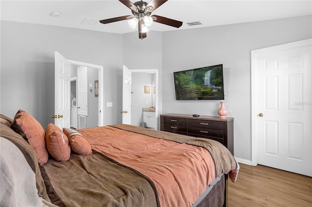 bedroom featuring ensuite bath, ceiling fan, light hardwood / wood-style flooring, and lofted ceiling