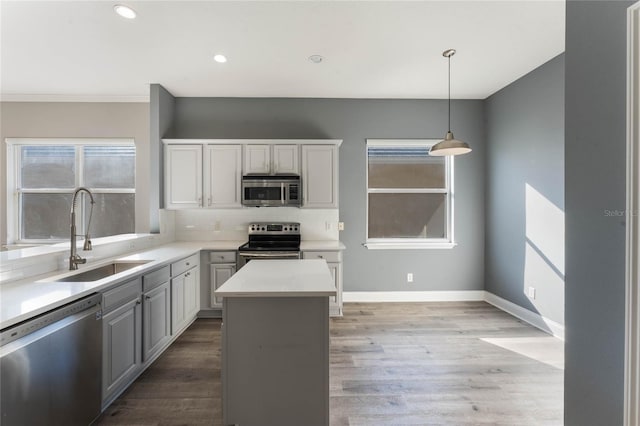 kitchen featuring sink, gray cabinets, hanging light fixtures, stainless steel appliances, and a kitchen island