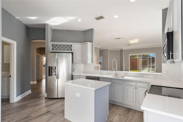 kitchen featuring sink, a center island, stainless steel appliances, light hardwood / wood-style floors, and white cabinets