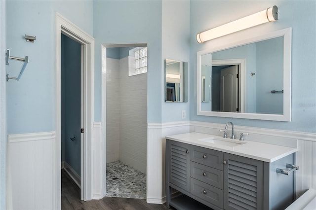 bathroom with hardwood / wood-style flooring, vanity, and a tile shower