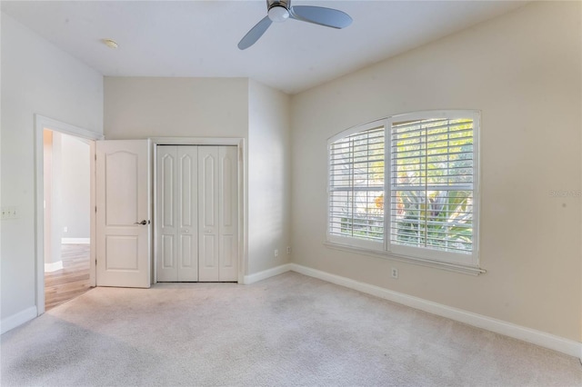 unfurnished bedroom with ceiling fan, light colored carpet, and a closet