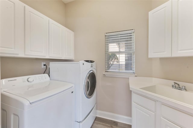 washroom featuring sink, washer and clothes dryer, cabinets, and light wood-type flooring