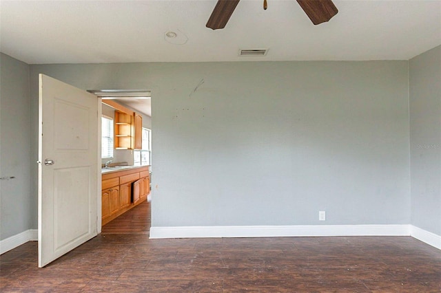 empty room featuring sink, ceiling fan, and dark hardwood / wood-style floors