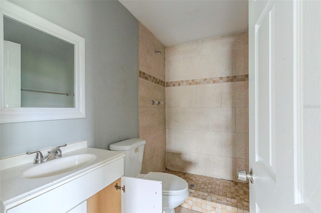 bathroom featuring tiled shower, vanity, and toilet