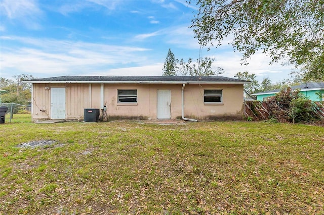 rear view of house featuring cooling unit and a yard