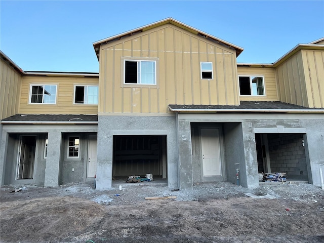 view of front of home with a garage, board and batten siding, and stucco siding