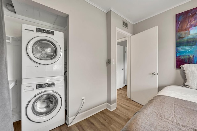 laundry room with crown molding, hardwood / wood-style floors, and stacked washer / drying machine