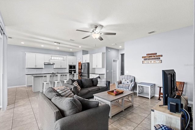 living room featuring a textured ceiling, ceiling fan, and light tile patterned floors