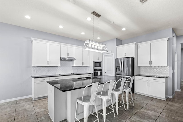 kitchen featuring white cabinetry, stainless steel appliances, and an island with sink