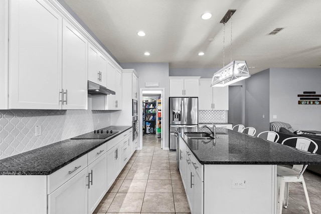 kitchen featuring white cabinets, decorative light fixtures, black electric stovetop, sink, and a center island with sink