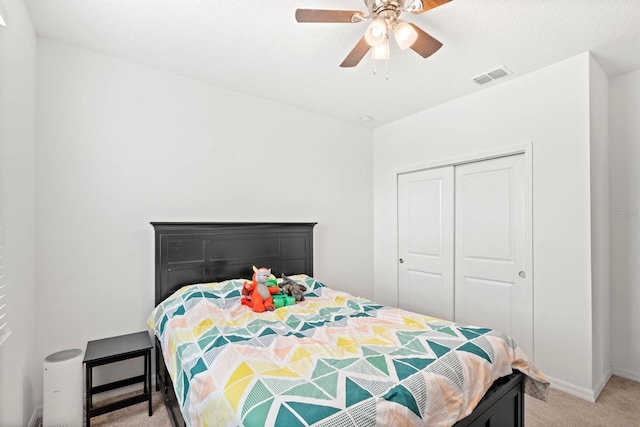 bedroom with ceiling fan, light colored carpet, and a closet