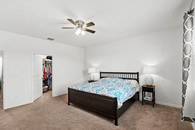 carpeted bedroom featuring ceiling fan, a closet, and a walk in closet