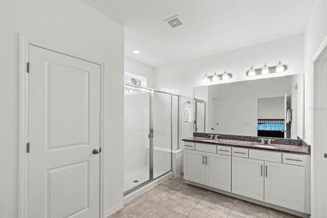 bathroom with a textured ceiling, tile patterned floors, walk in shower, and vanity