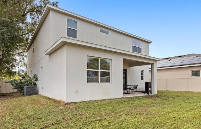 back of property with central air condition unit, a patio area, and a yard