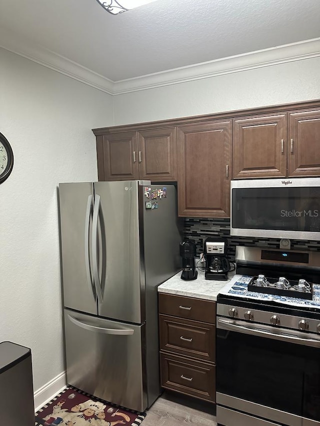 kitchen with tasteful backsplash, dark brown cabinetry, appliances with stainless steel finishes, and ornamental molding