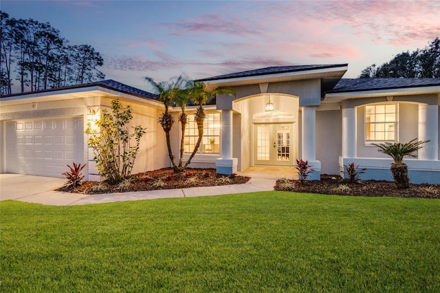 view of front facade featuring a garage, french doors, and a lawn