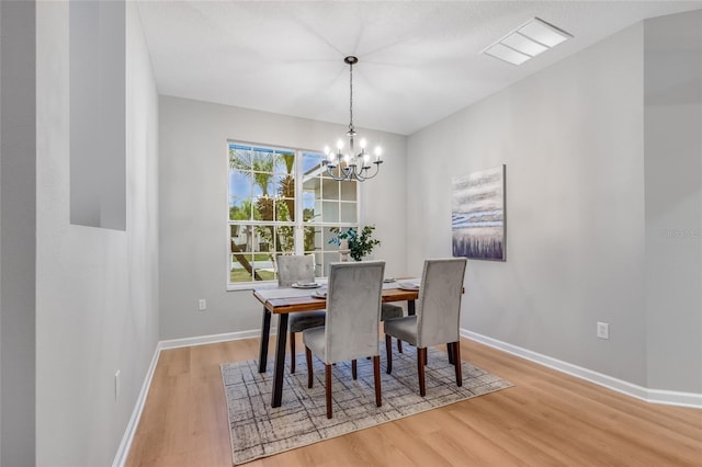 dining area with light hardwood / wood-style floors and a chandelier