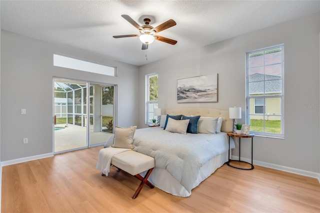 bedroom with ceiling fan, access to exterior, light hardwood / wood-style floors, and multiple windows