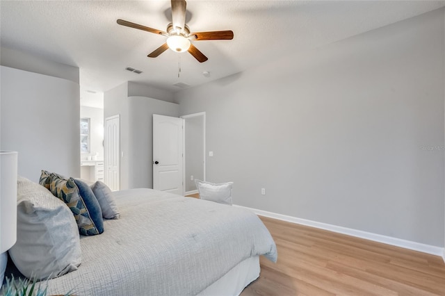 bedroom with ceiling fan, light hardwood / wood-style floors, connected bathroom, and a textured ceiling