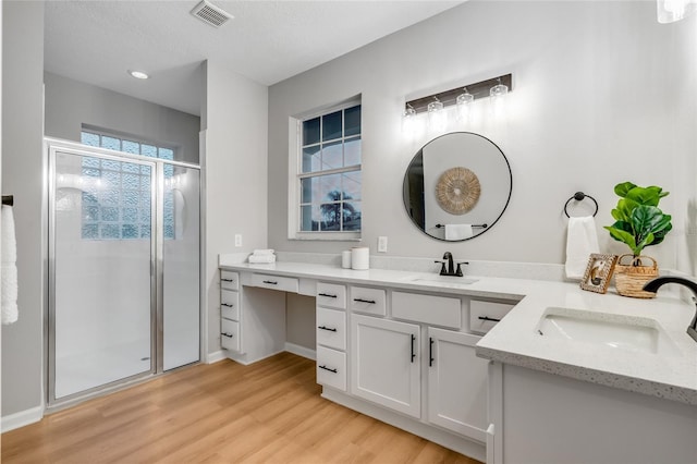 bathroom featuring a textured ceiling, hardwood / wood-style floors, an enclosed shower, and vanity