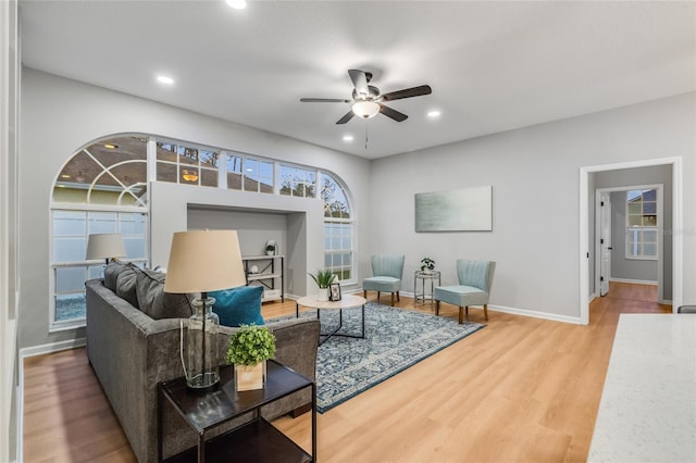 living room with ceiling fan, plenty of natural light, and wood-type flooring