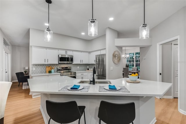 kitchen with appliances with stainless steel finishes, decorative backsplash, decorative light fixtures, white cabinets, and sink